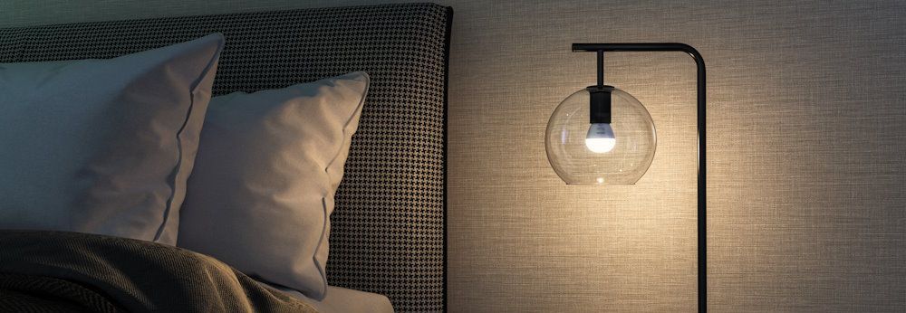 Beleuchtete Nachttischlampe neben Bett